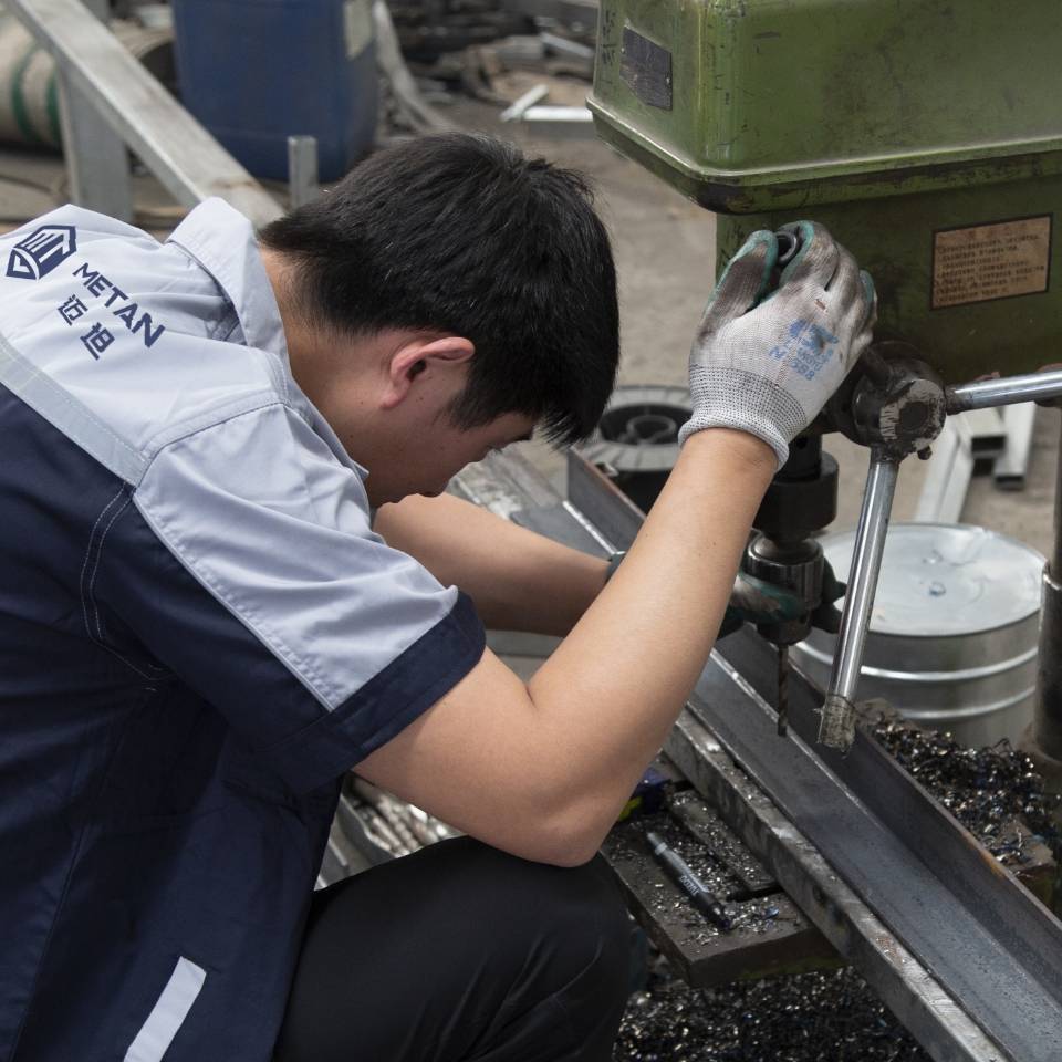 The worker is punching holes on the angle steel