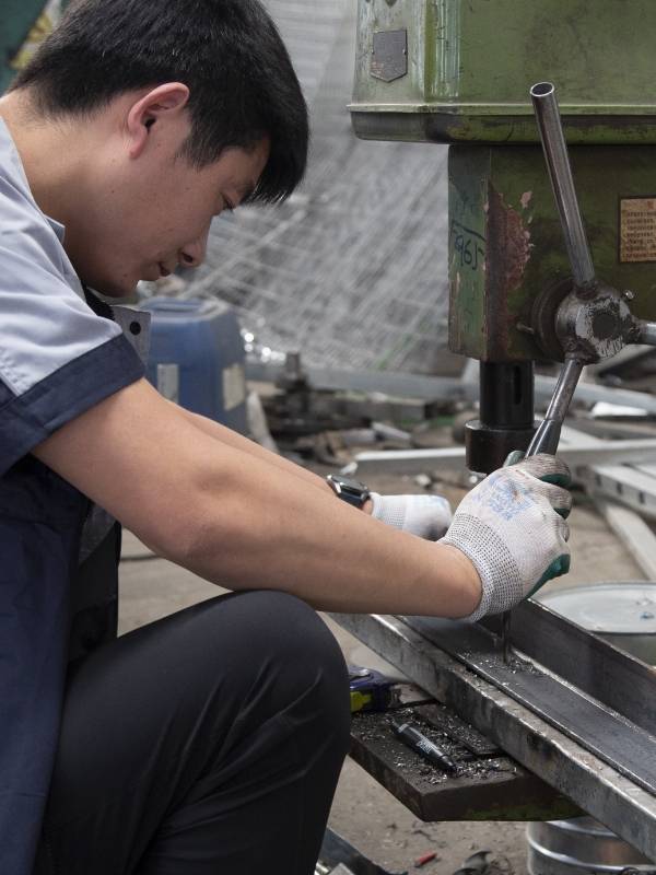 Our worker is punching holes on angle steel for machine guarding system.